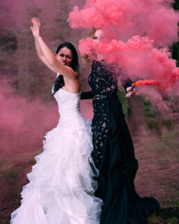 zwei Frauen schwarz und weißes Kleid haben eine rote Leuchtfackel in der Hand